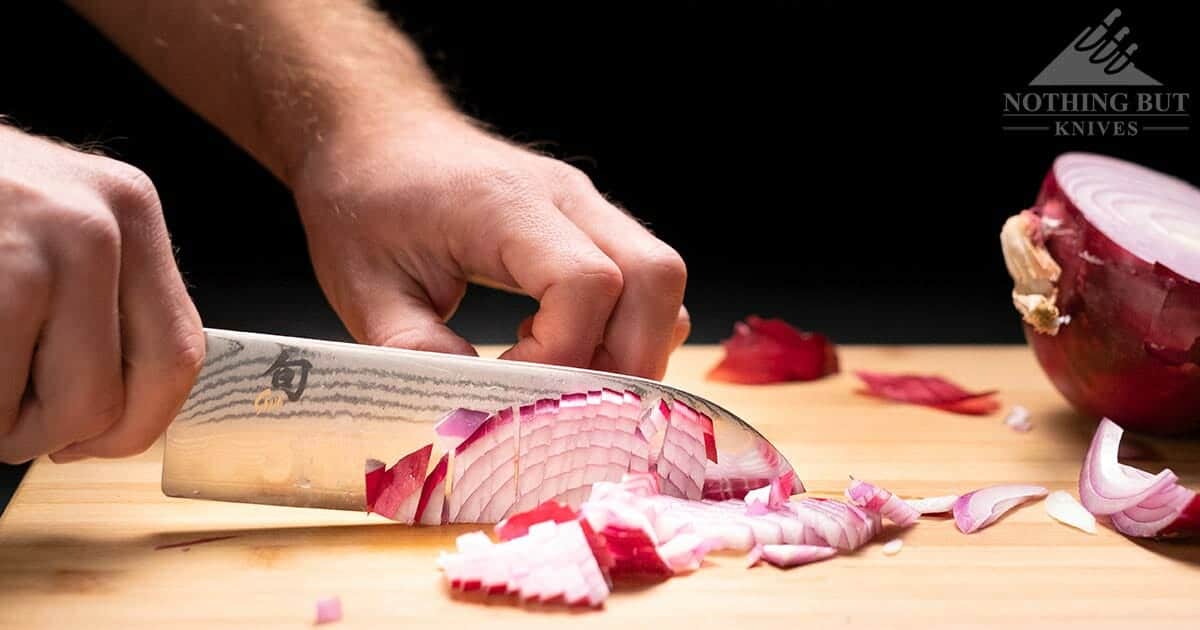 A close up of a man dicing an onion with the Japanese made Shun Classic Santoku knife. 