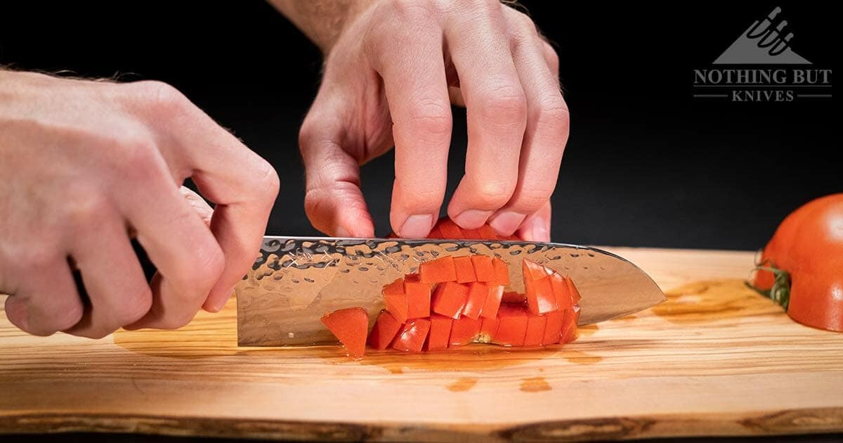 A man's hands dicing a tomato with the Enso HD santoku knife. 