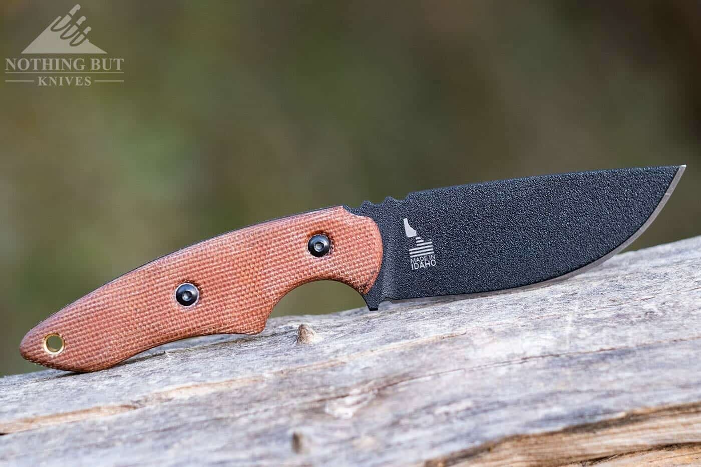 The TOPS 3-Pointer tactical neck knife with 1095 RC steel on a log outdoors. 