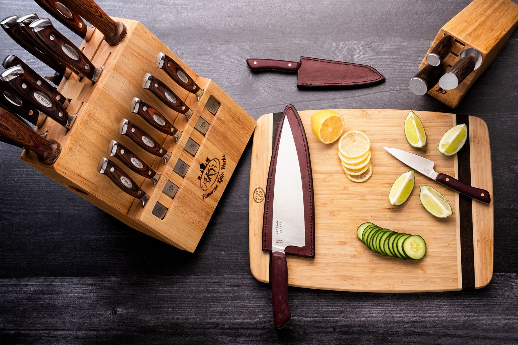 A top-down view of three different high-end knife sets with a cutting board and sliced fruit and vegetables.