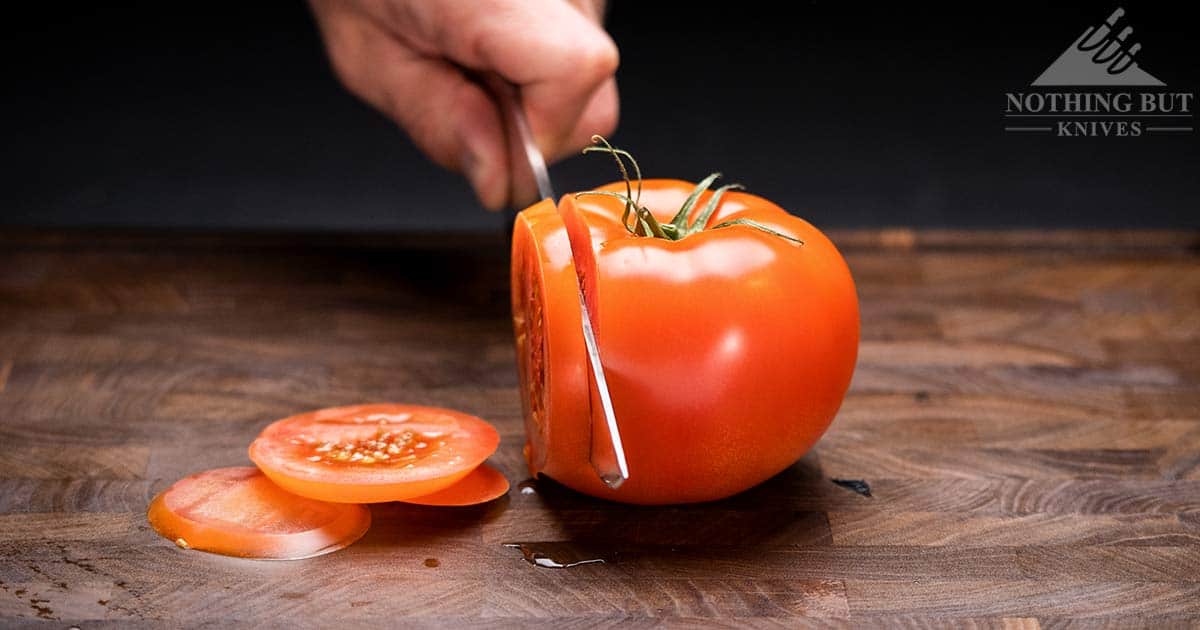 A tip forward shot of the Cangshan TC chef knife slicing through a tomato. 