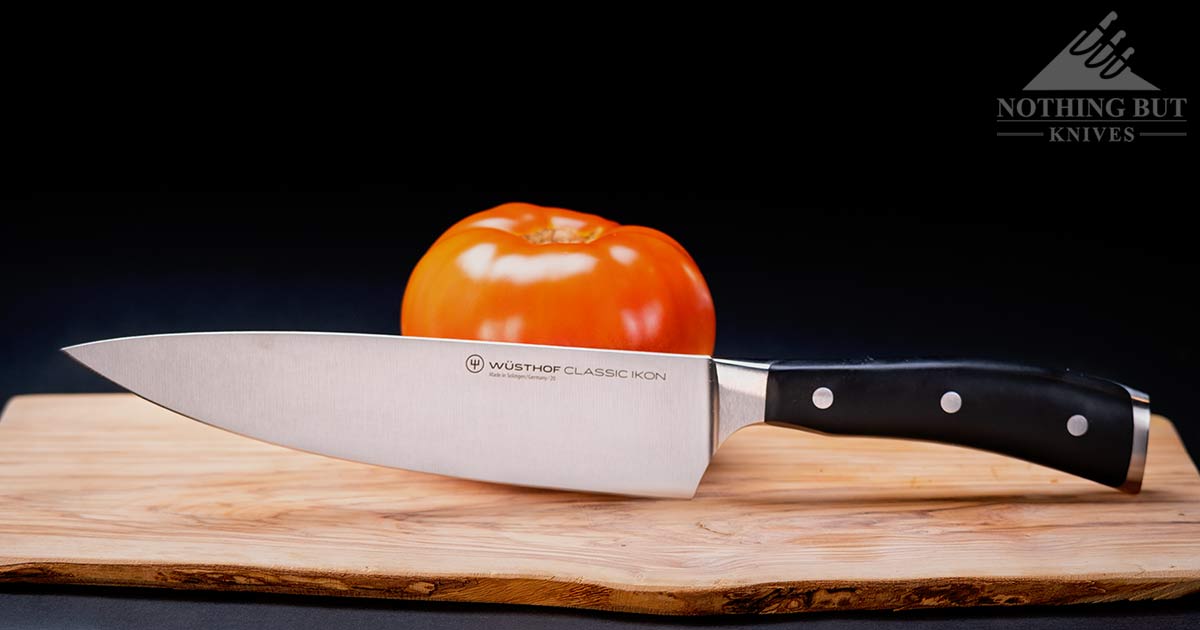 Wusthof Classic Ikon chefs knife on a wood cutting board with a tomato.