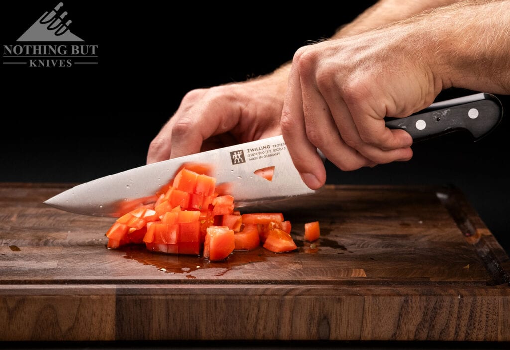 Best High-End Knife Sets For Professional Or Home Use - Image 37 A close-up of the Zwilling Professional S chef knife dicing a heirloom tomato.