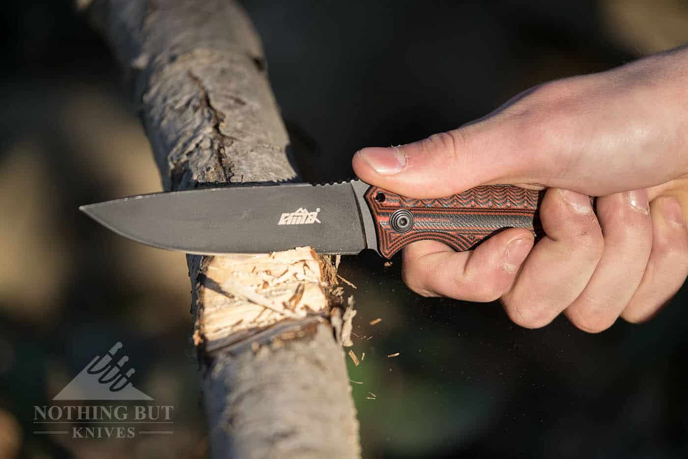 The Cima G20 Survival Knife chopping a tree limb in the forest.