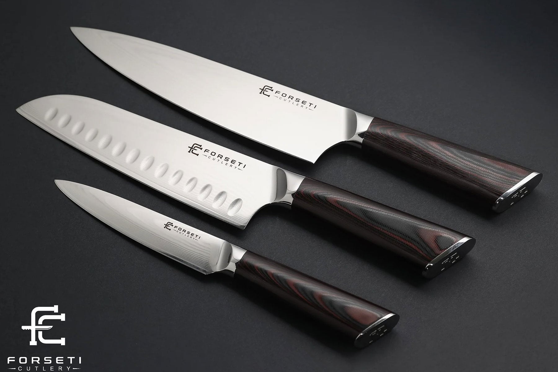 Best Kitchen Knife Sets Under $300 - Image 9 A slightly angled overhead view of the three knives included in the Forseti Cutlery 3-piece kitchen knife set on a dark background.