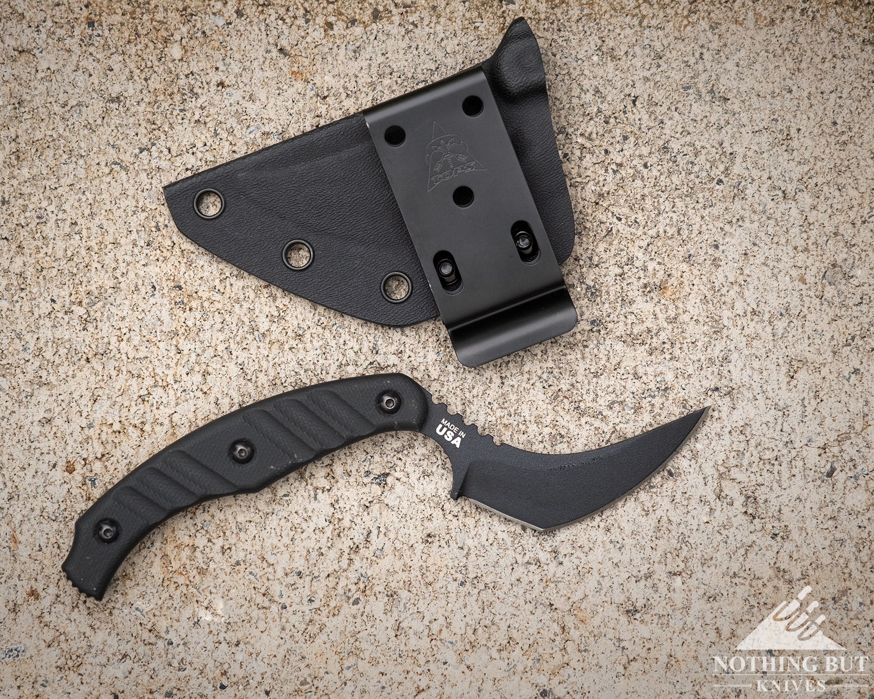 Best Horizontal Carry Knives - Continuous Update - Image 55 An overhead view of the TOPS Ephyra tactical knife next to its kydex sheath on a cement block.