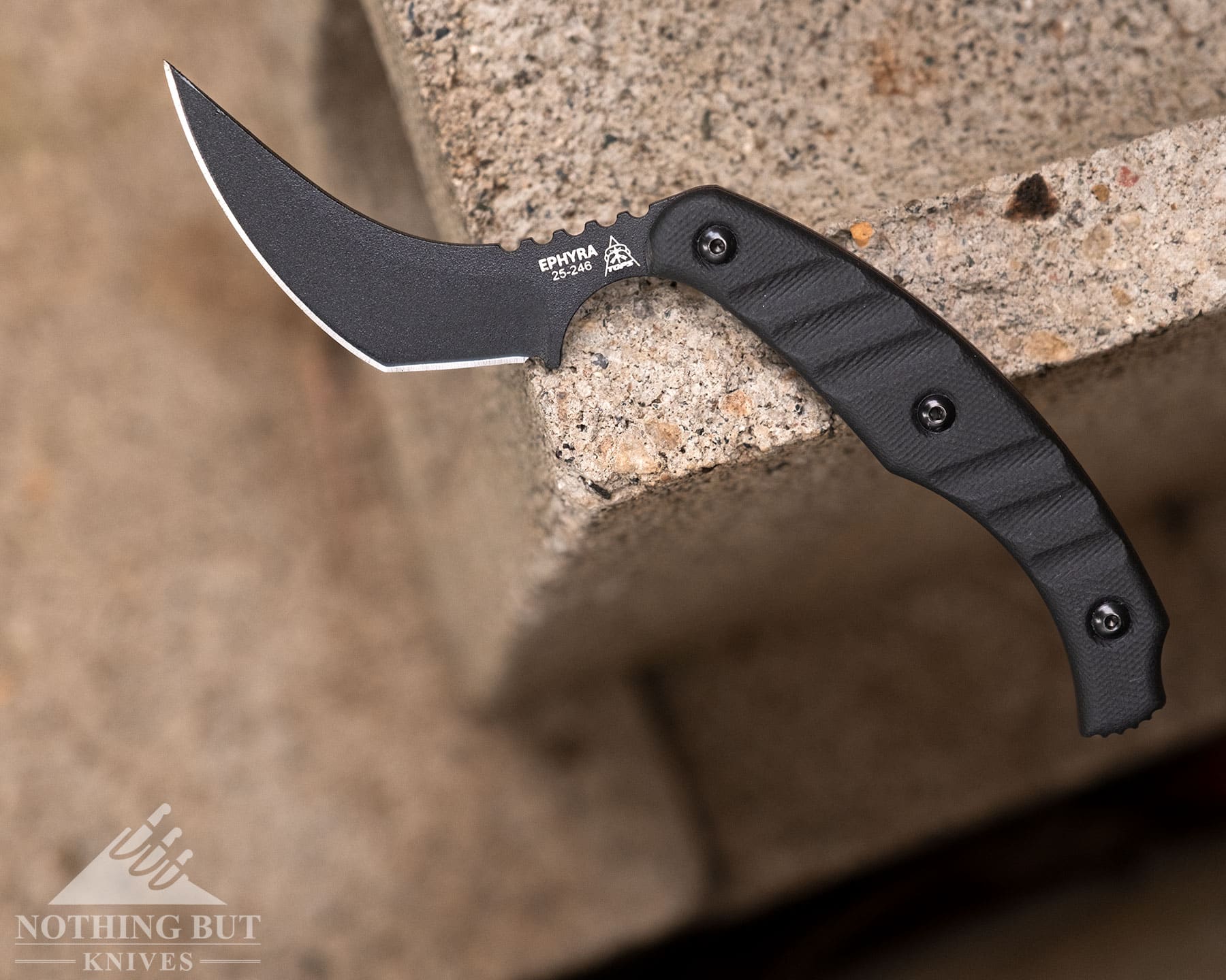 Best Horizontal Carry Knives - Continuous Update - Image 54 An overhead view of the TOPS Ephyra tactical knife balanced on the edge of a cinderblock.