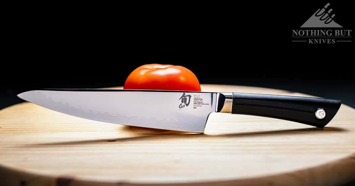 The Shun Sora 8 invh chef knife on a cutting board next to a tomato.