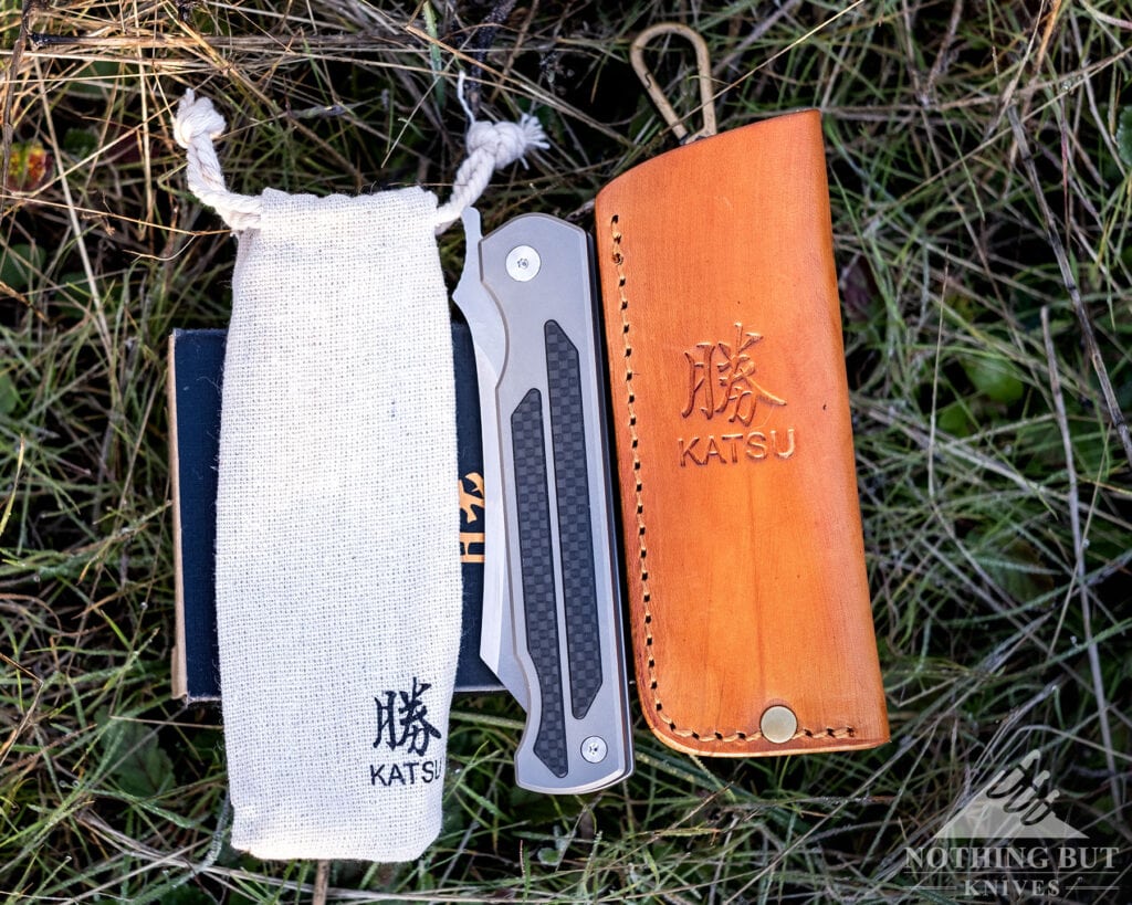 A Few Of Our Favorite Japanese Pocket Knives - Image 8 An overhead view of the Katsu Titanium Camping Knife shown here with its leather sheath and Hessian pouch.