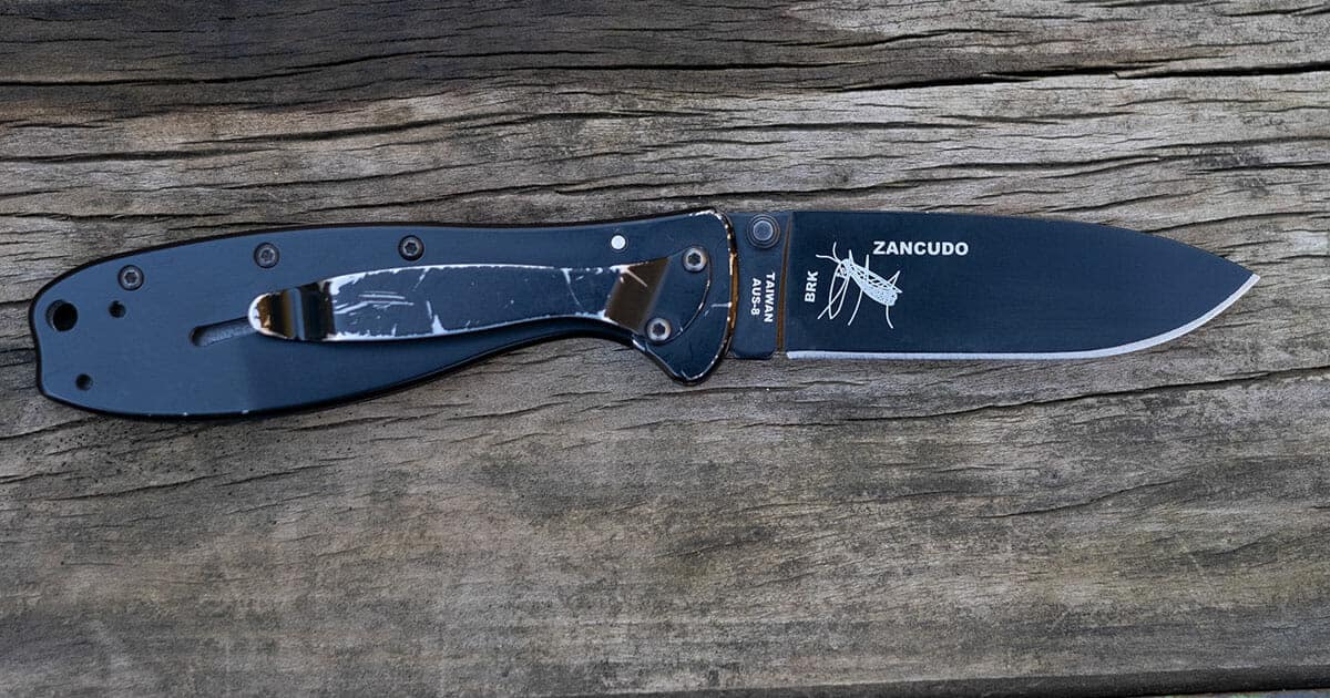 The Esee Zancudo pocket knife in the open position on a wood background. 