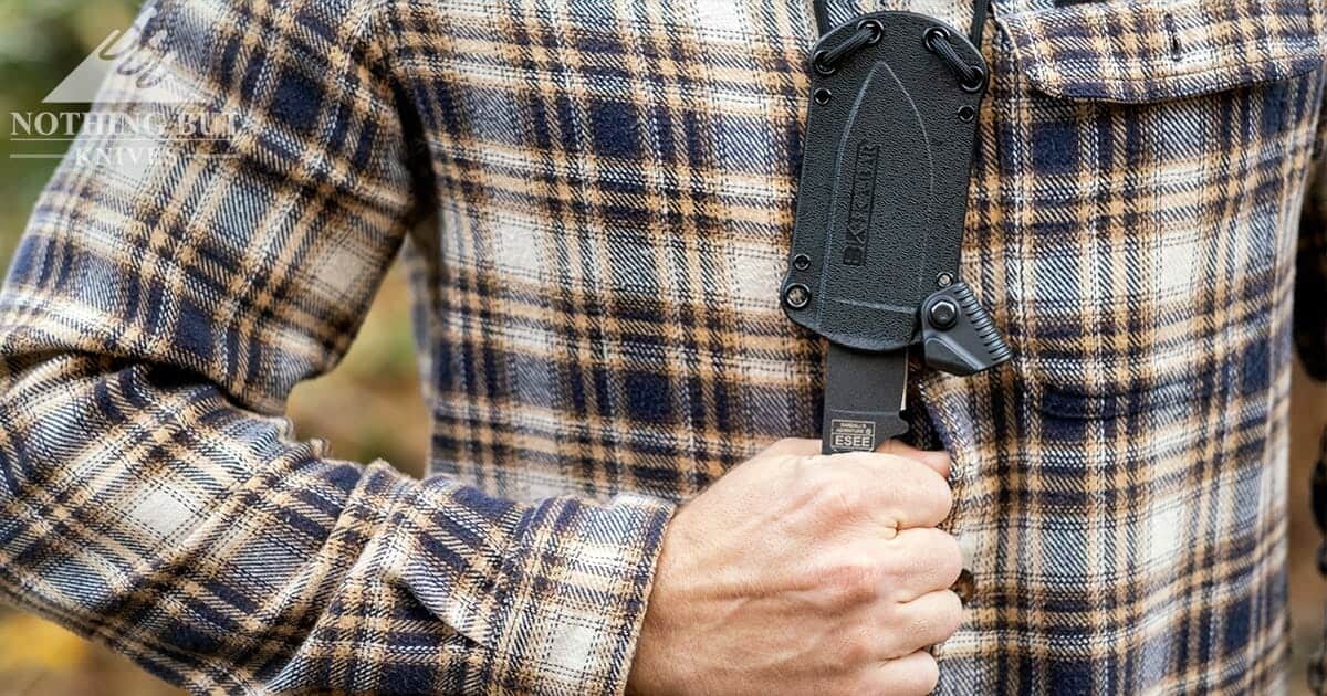 The Ka-Bar Becker BK14 neck knife on a man's cheft being drawn from it's sheath. 