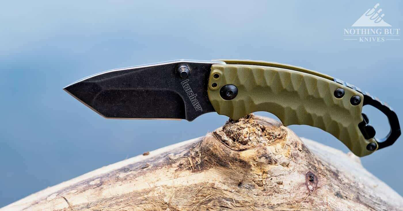 The Kershaw Shuffle pocket knife outdoors on a log next to a river.