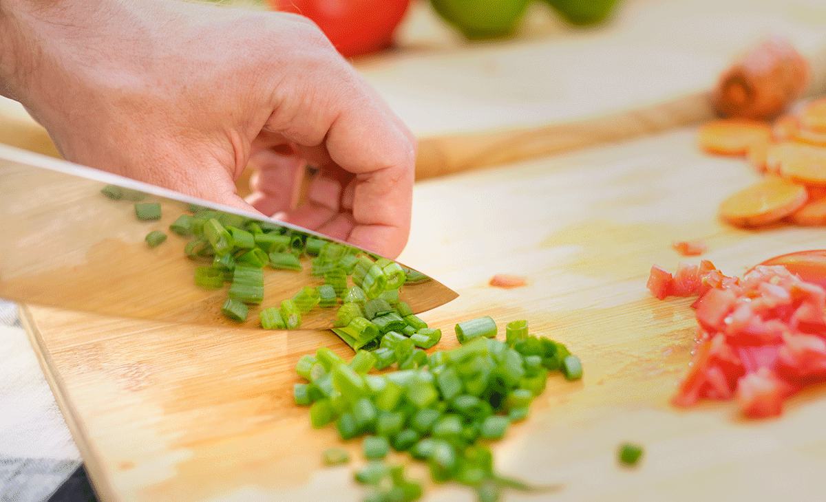 Chef knife cutting green onions. 