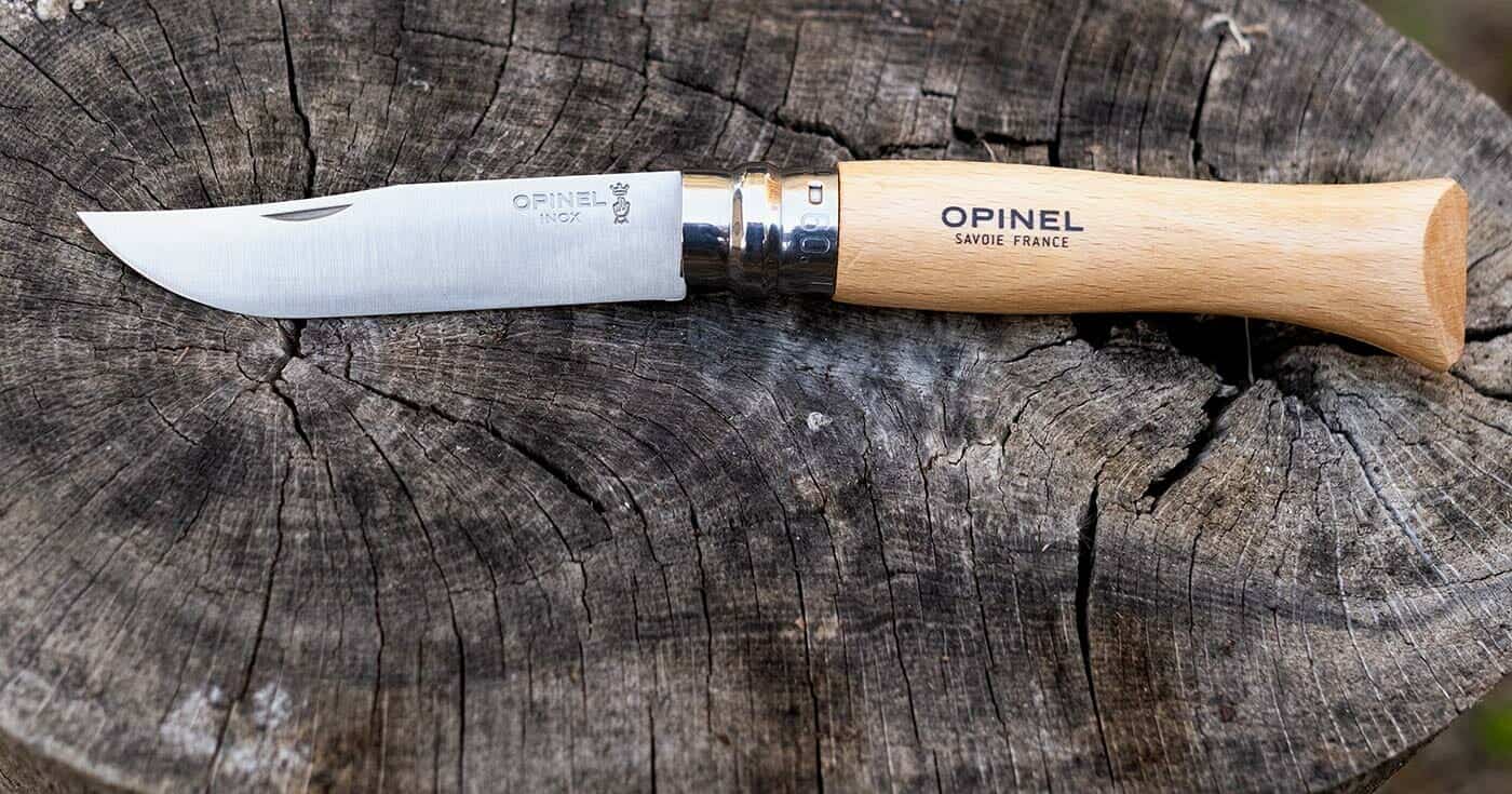 Best Hard Use Pocket Knives Under $50 And $100 - Image 27 The Opinel Number 9 open on a tree stump outdoors.