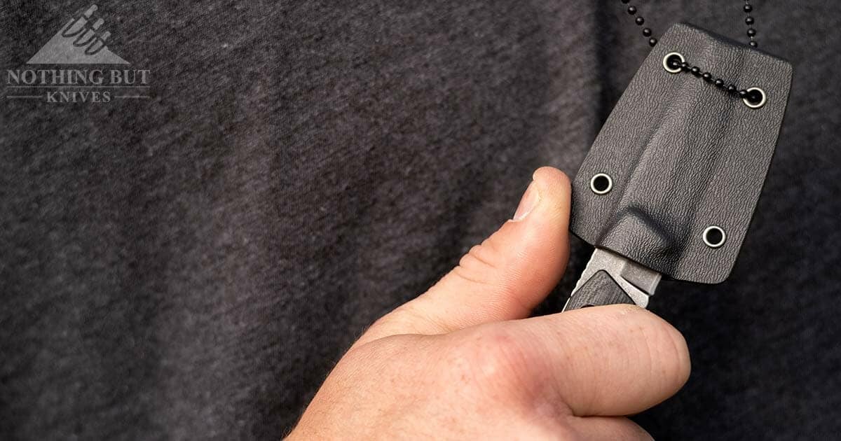 The Best Neck Knives With Good Sheaths 25 The Schrade 13SM drop point neck knife being drawn from it's sheath by a person's hand.