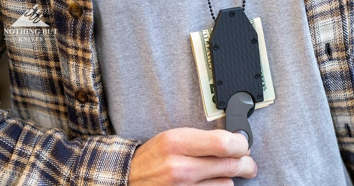 A man removing the Schrade SCHCC1 from it's money clip sheath while it is around his neck