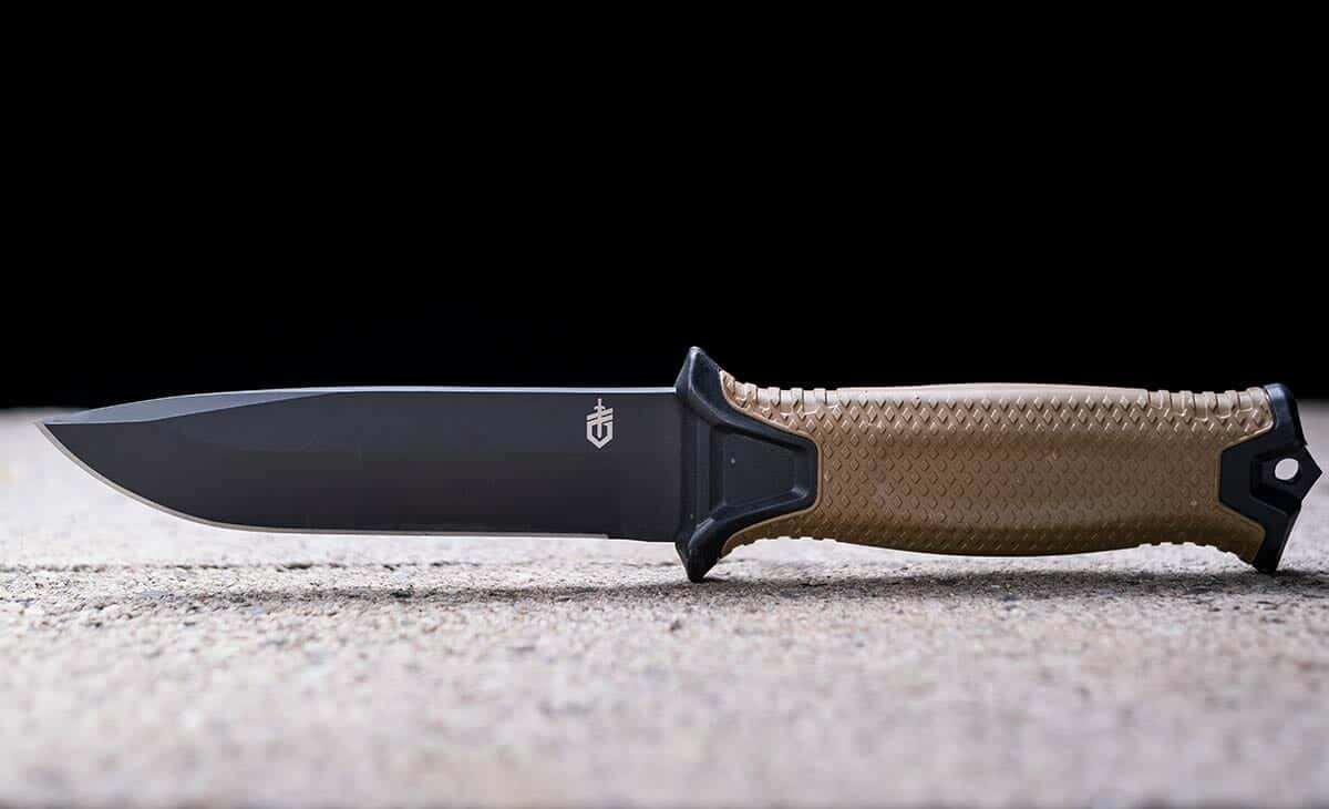 The Gerber StrongArm fixed blade tactical knife on cinderblocks in front of a black background. 
