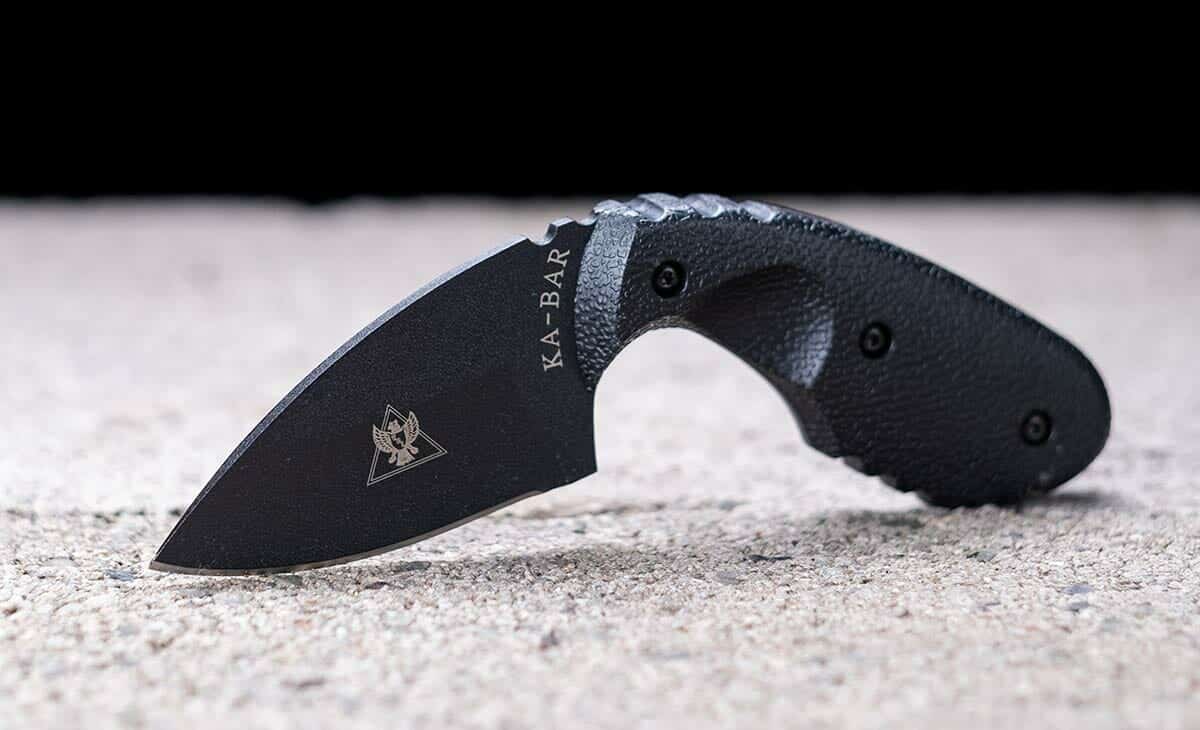 The Ka-Bar TDI compact tactical knife on a cinderblocks in front of a black background.