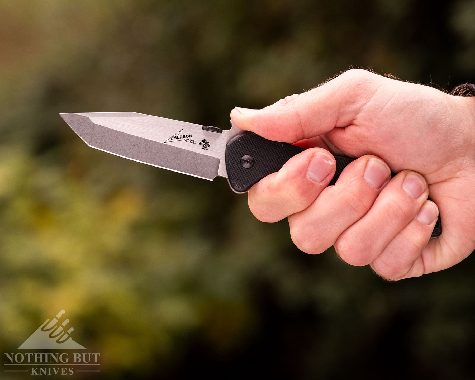 The Best Tactical Knives From Our Favorite Brands - Image 40 A Kershaw CQC series knife being held in a person's right hand in front of a blurry, green background.