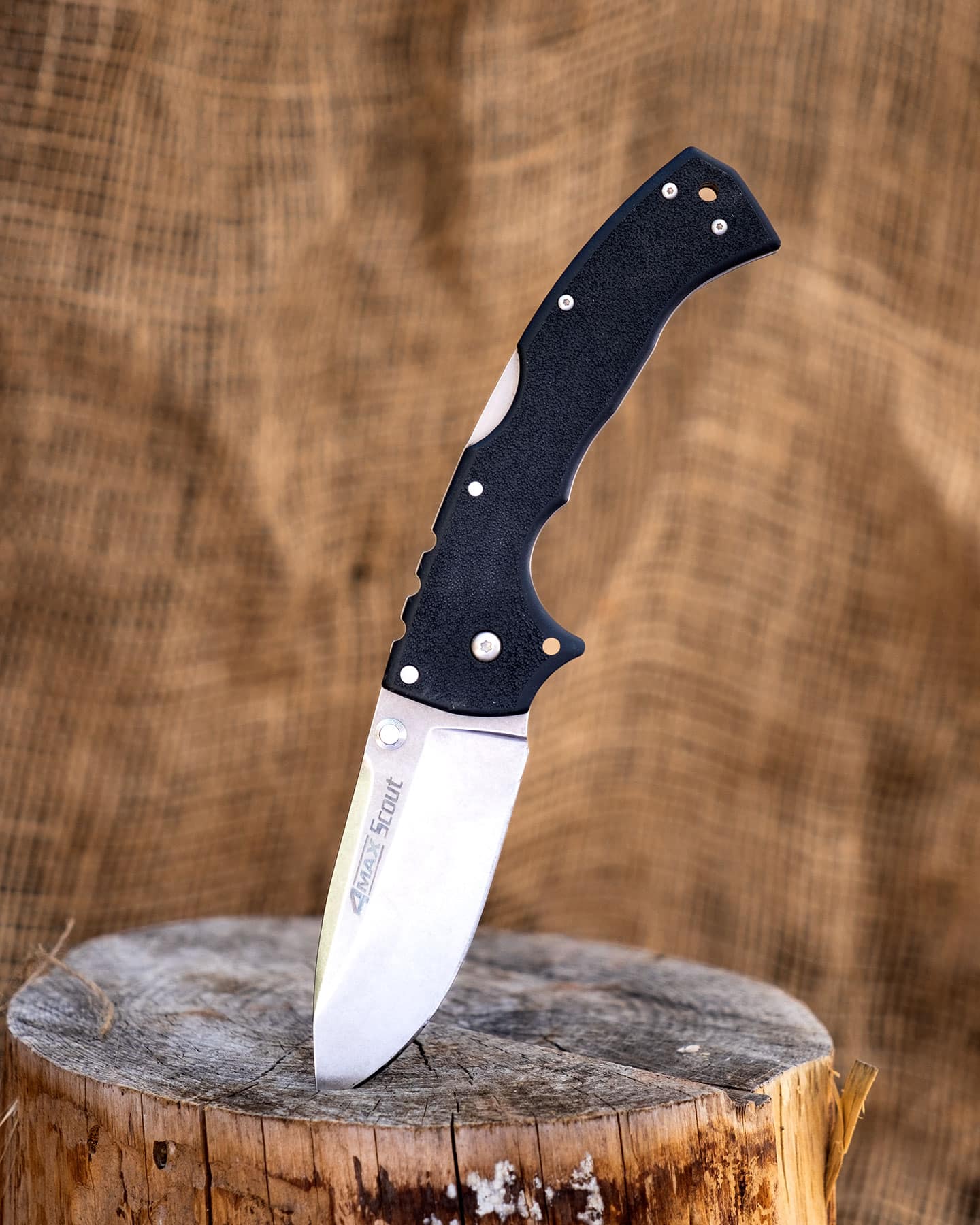 The Cold Steel 4-MAX Scout pocketknife in the open position with the tip sticking in a tree stump.