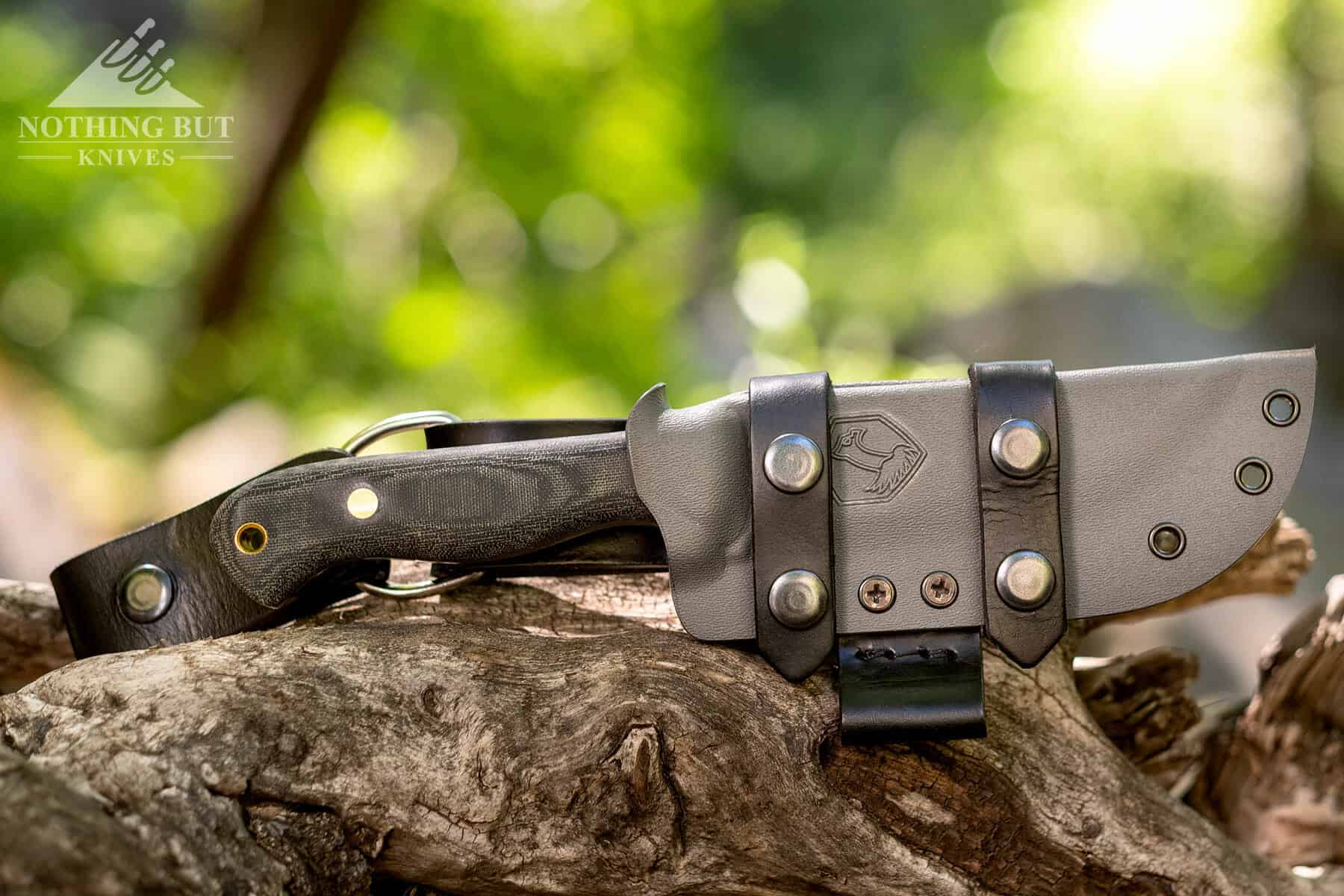 The Condor SBK with it's sheath sitting on a log in the wilderness.