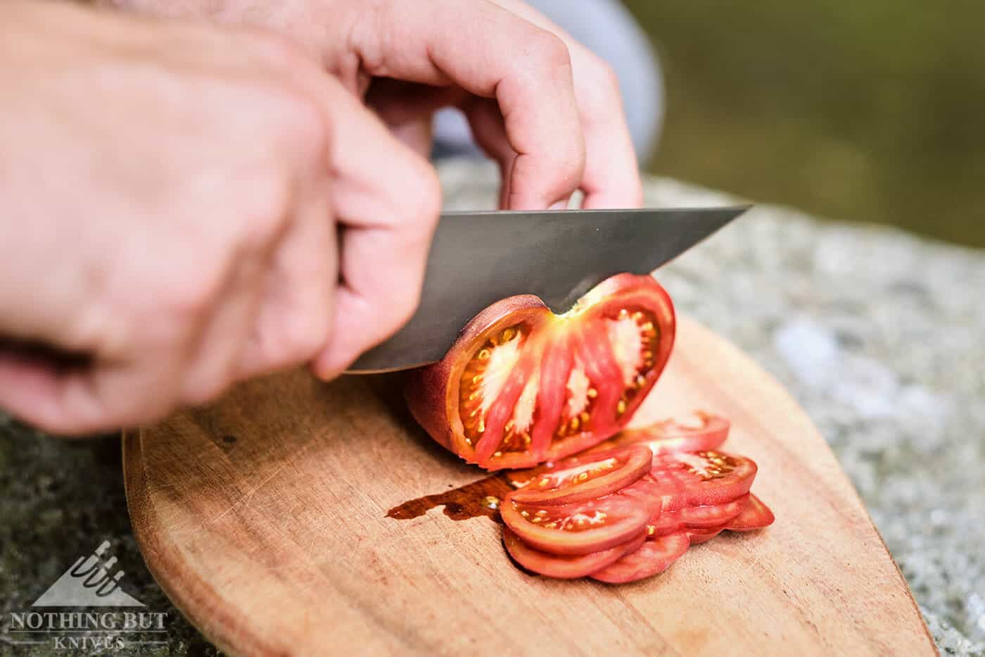 Slicing tomatoes effortlessly with a knife that is primarily a butcher knife. 
