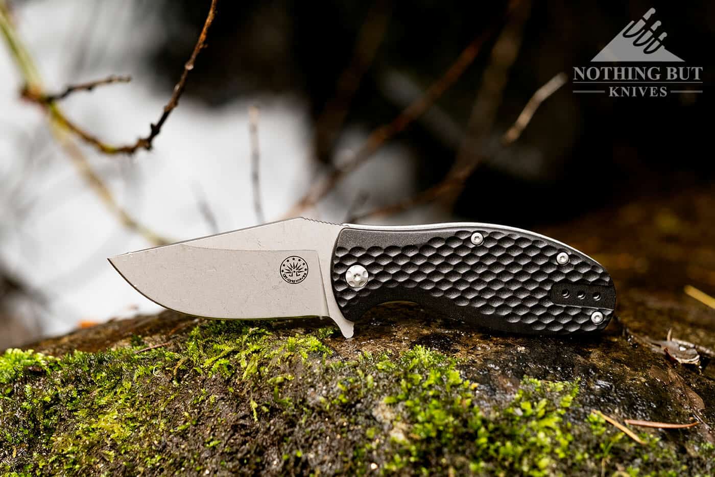 The Off-Grid Badger on a mossy rock on the edge of a mountain creek. This knife is great for dirty work.