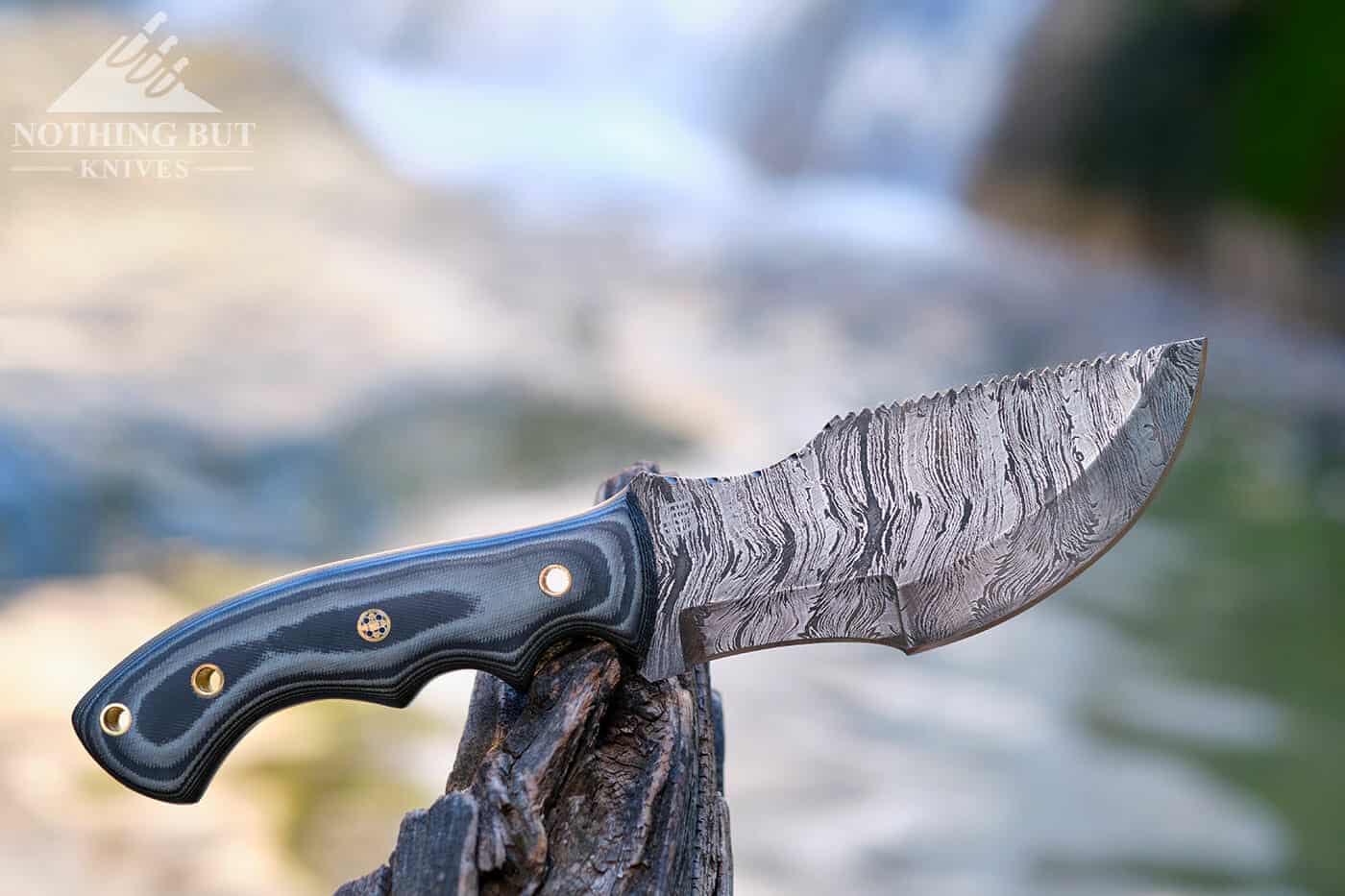 Damascus steel survival knife at the base of a waterfall in a mountain creek. 