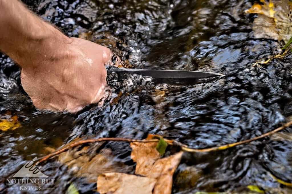 A mans hand pulling the Buck GCK tactical knife from a creek.
