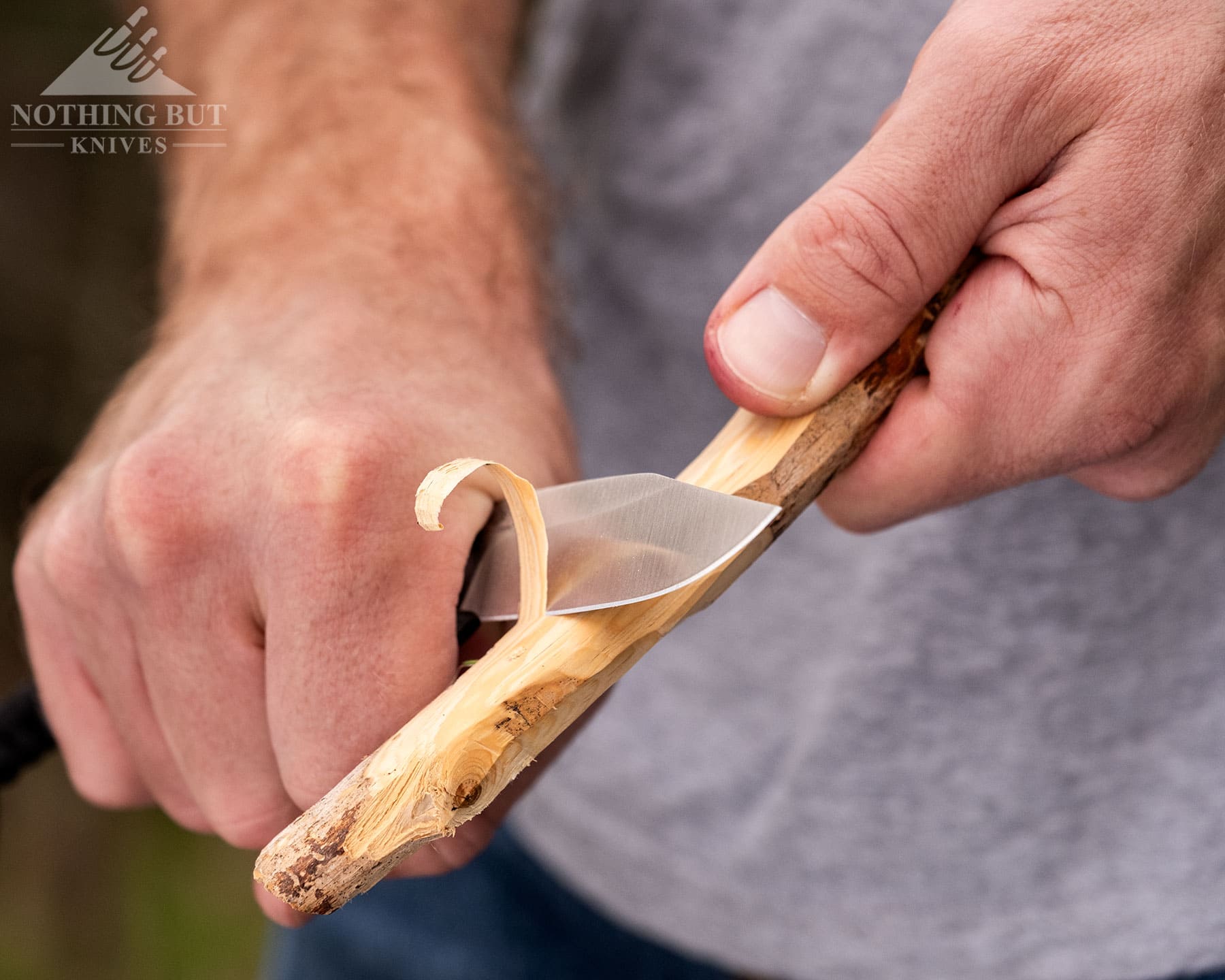 A close-up of the Knafs Lander 4 fixed blade knife being used to sharpen a stick. 