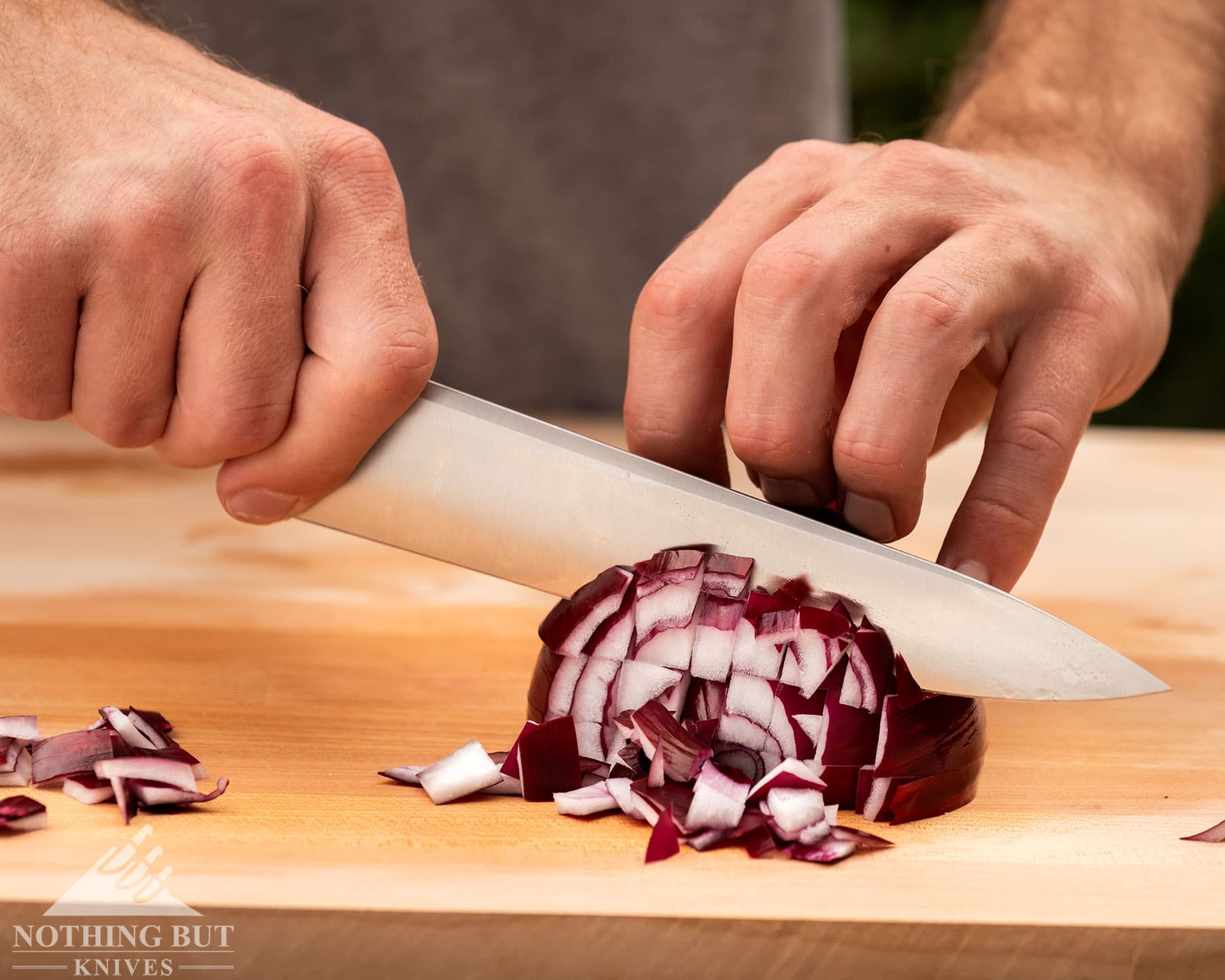 The Civivi Cibus chef knife dicing a red onion. 