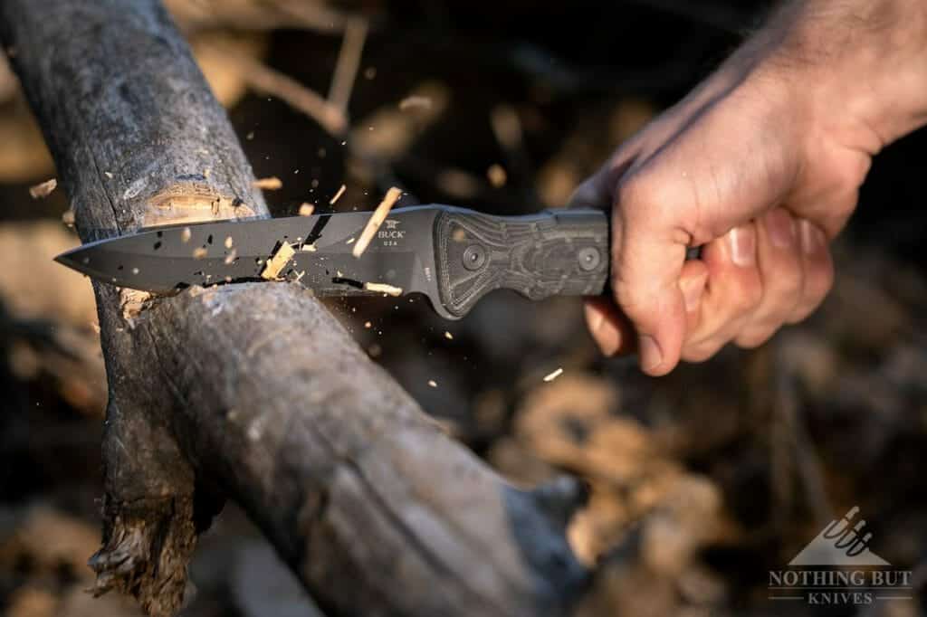 The Sniper Gray Buck GCK knife chopping a log in the wilderness. 