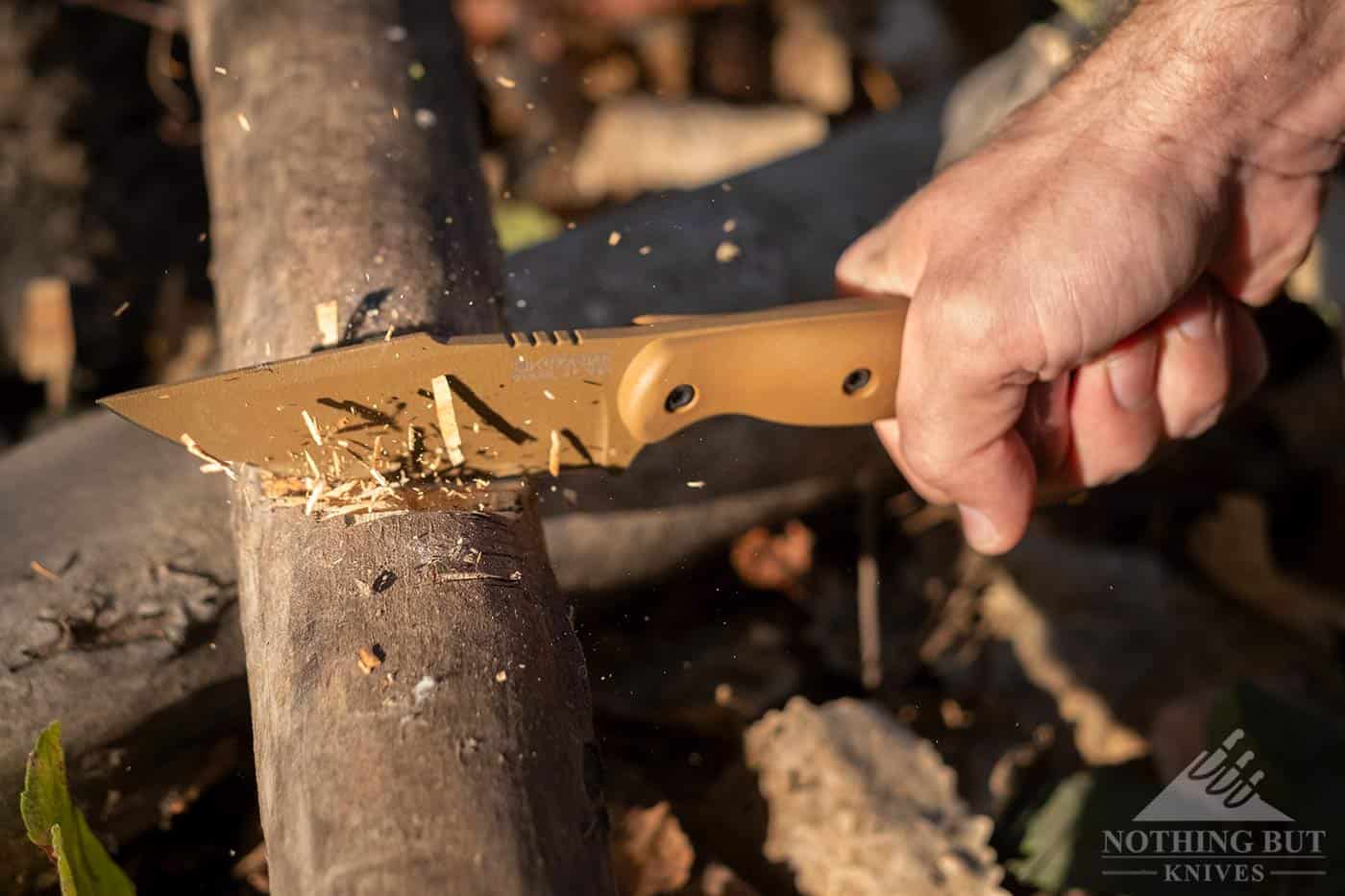 The Ka-Bar Becker BK18 tactical survival knife chopping a tree branch.