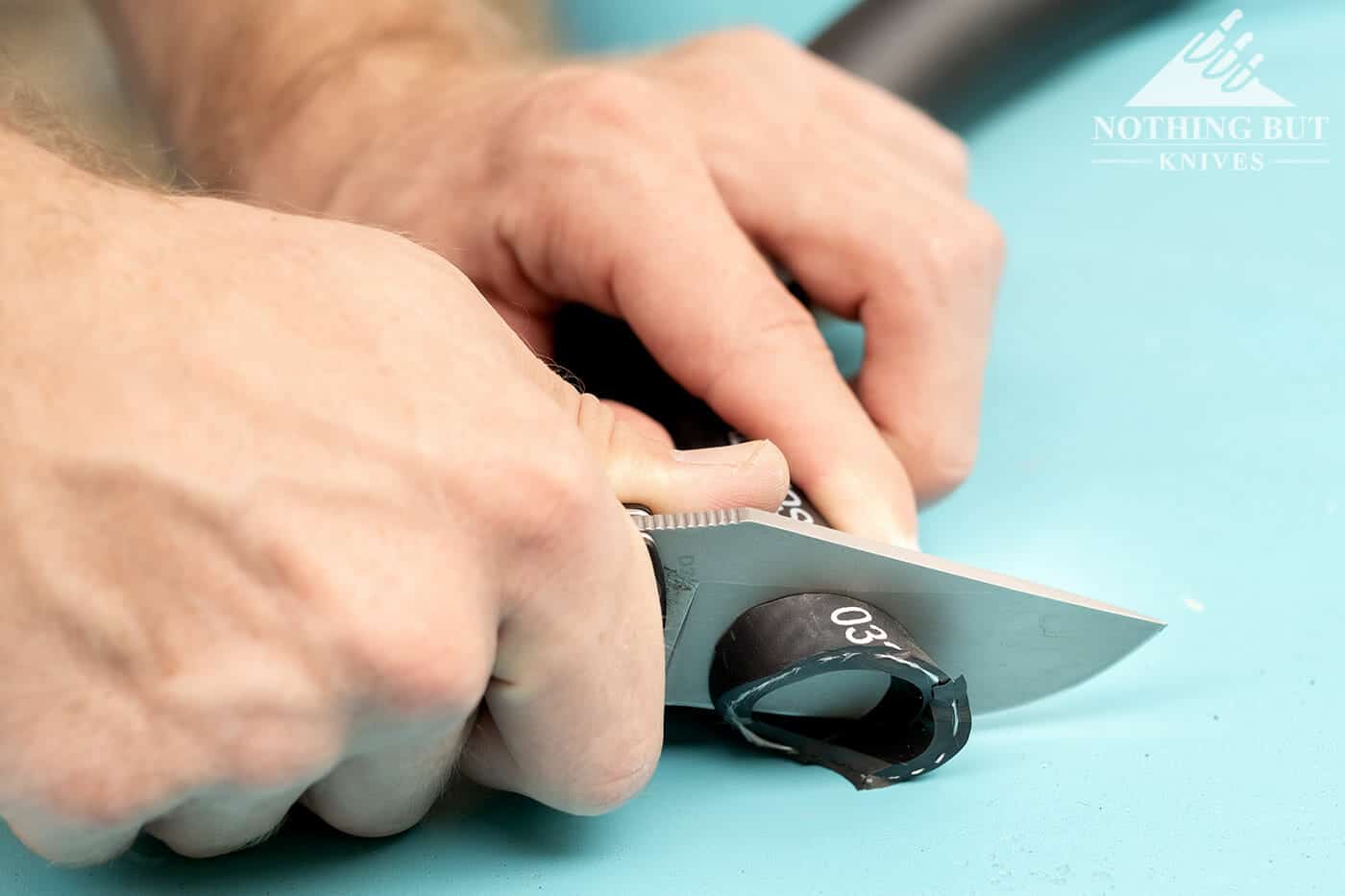 Off-Grid Knives Badger Review - Image 4 Cutting a thick rubber hose with a hard use pocket knife.