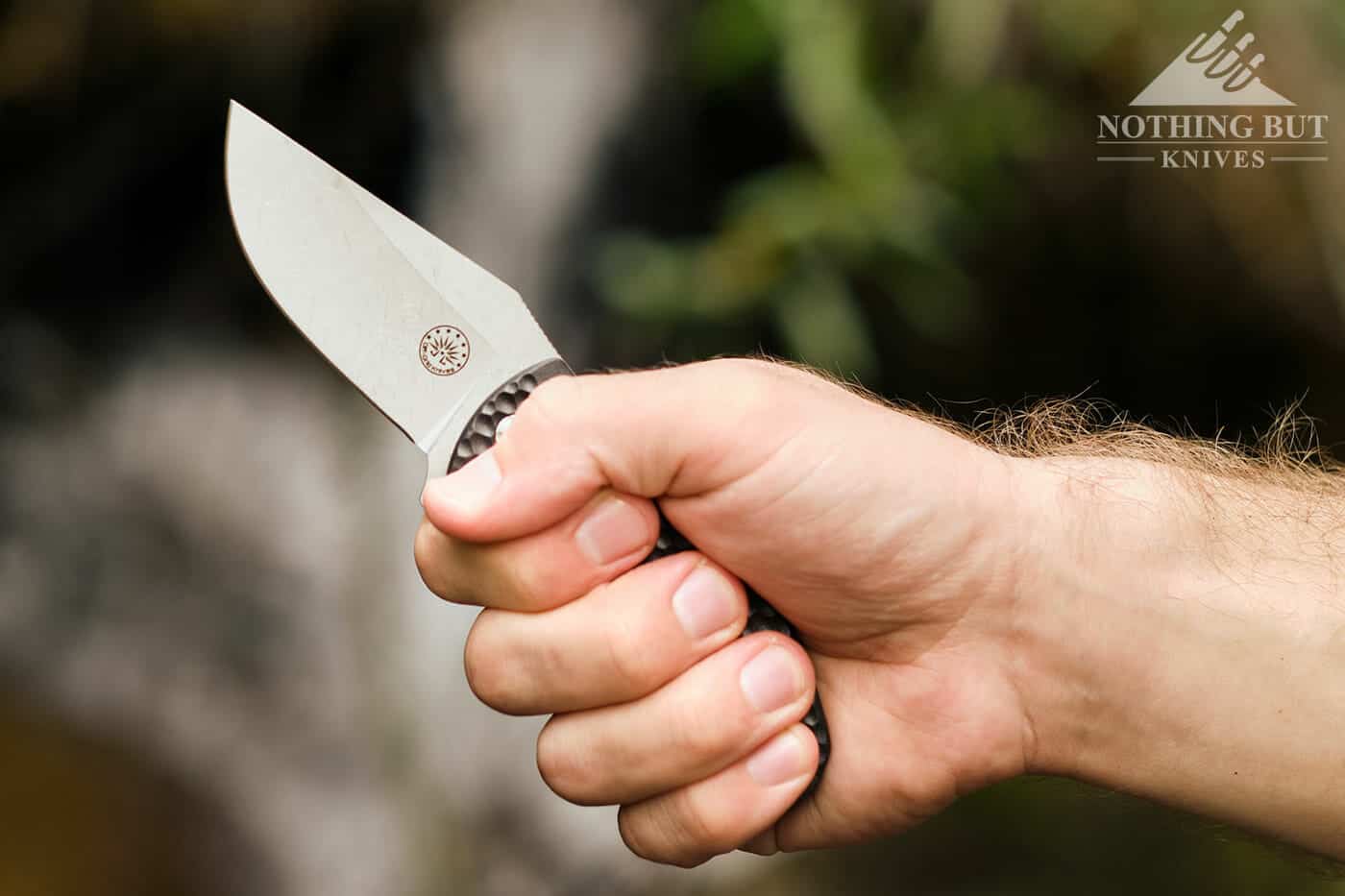 A man's hand gripping the handle of the Badger folding knife. 