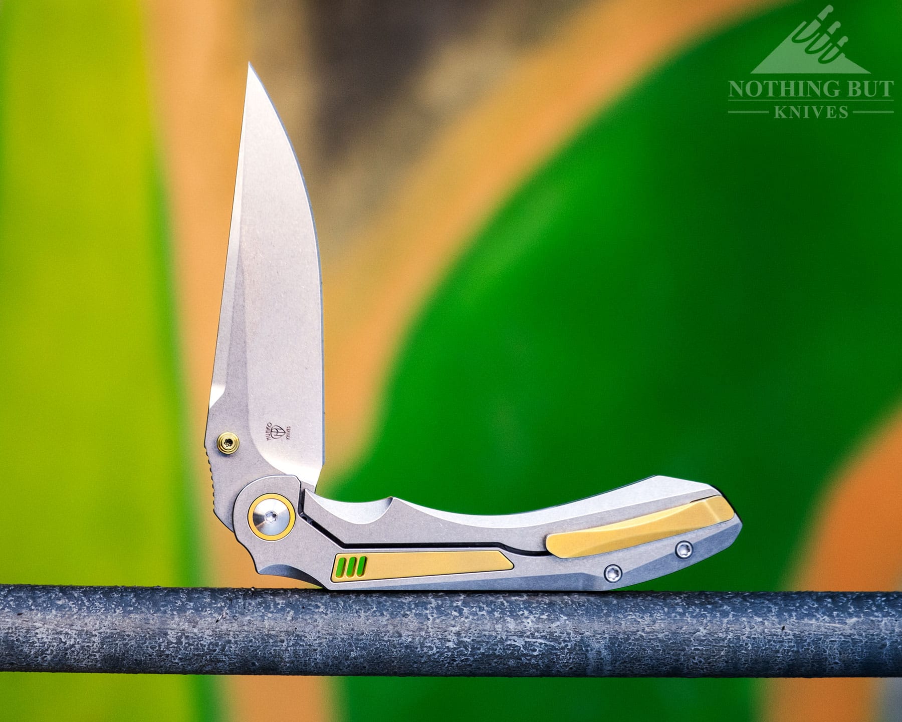 The Orbital Fornax EDC knife on a steel ladder in front of a green and yellow graffiti wall. 