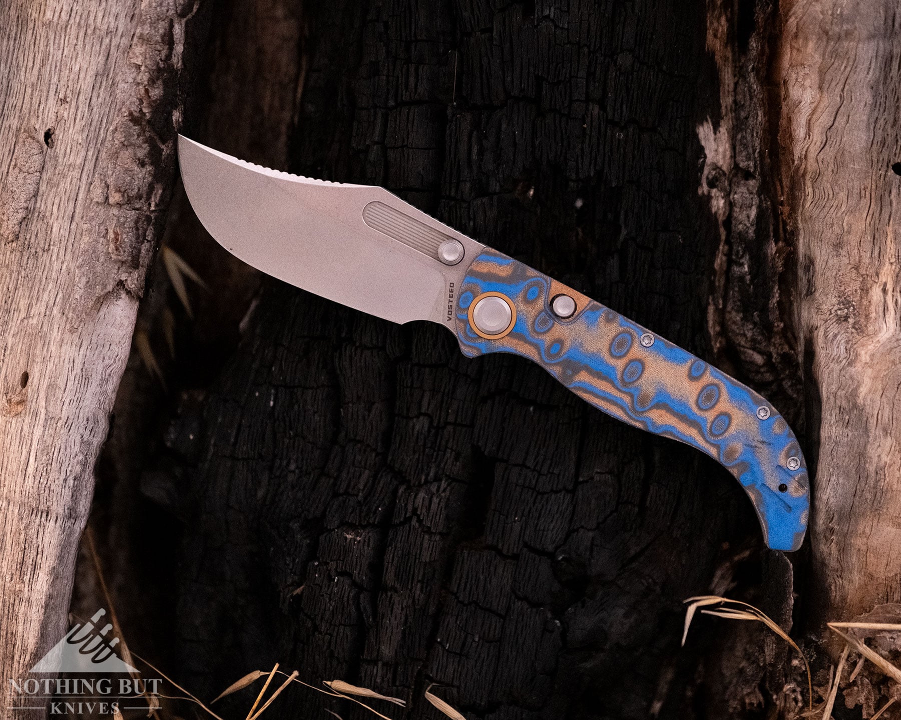 The Vosteed Naga pocket knife with its blade in the open position inside a hollowed-out tree. 