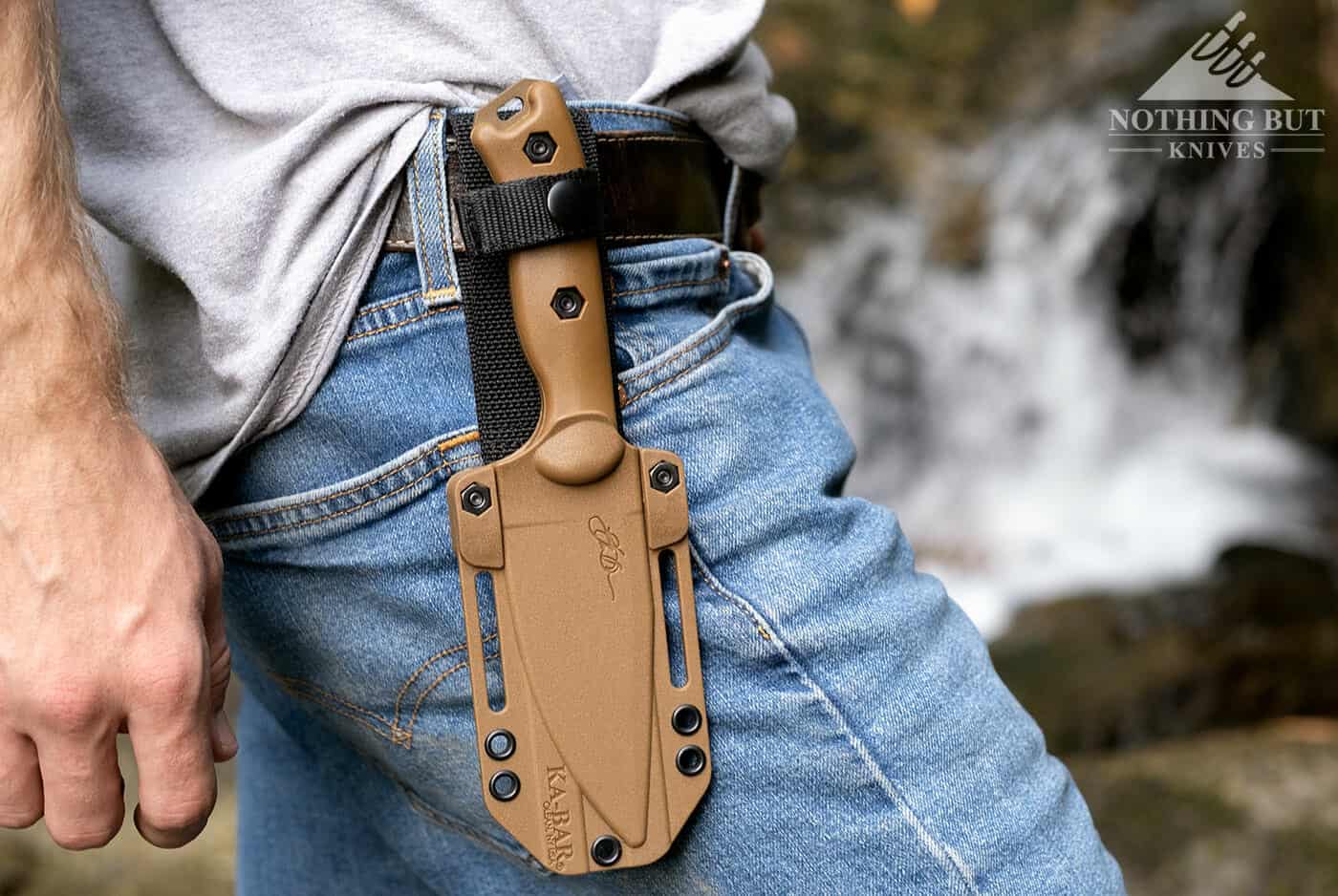 The Ka-Bar Becker BK18 Harpoon knife in it's sheath in on a man's waist in the wilderness. 