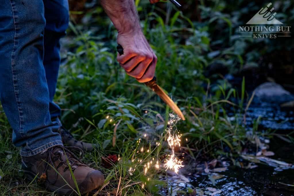 Throwing's spark with the Buck Ground Combat Knife and a ferro rod in the woods.