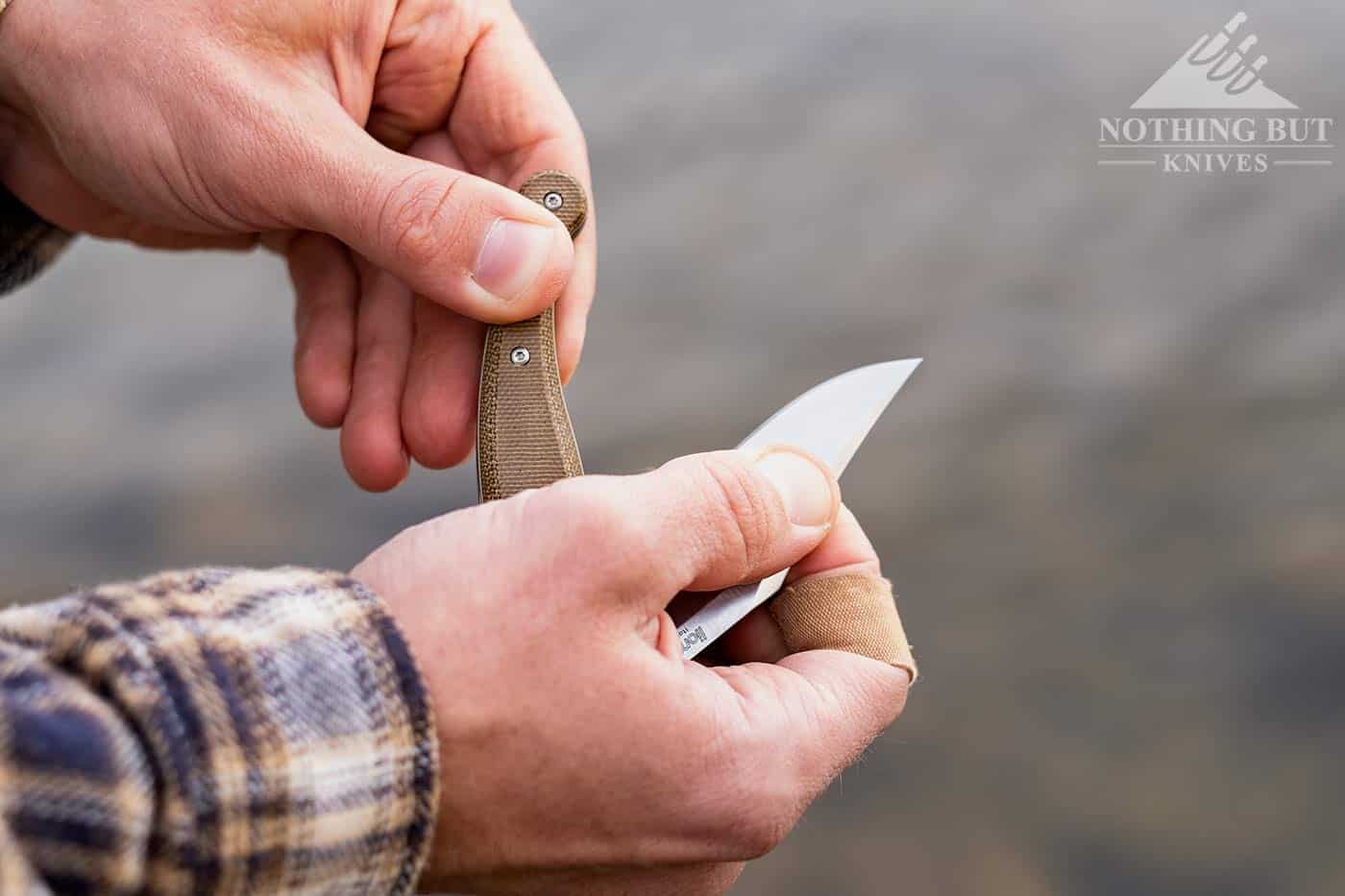 A man's hands closing the LionSteel Gitano knife above a river.
