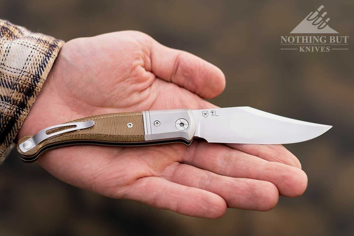 The LionSteel Gitano folding knife open and laying flat in the palm of a man's hand.