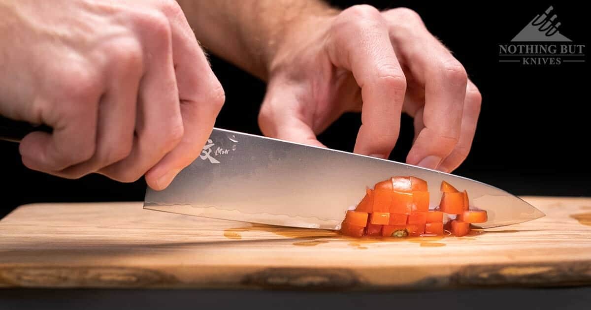 Yaxell Mon Gyuto 8 Inch Chef Knife Review - Image 6 A close-up of the Yaxell Mon chef knife chopping a ripe tomato.