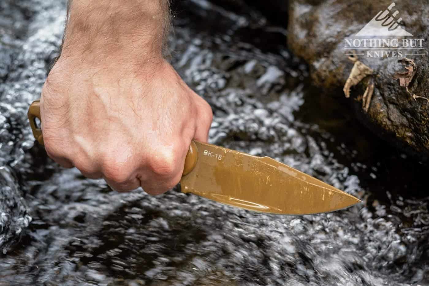 The Ka-Bar Becker BK18 in a man's hand being removed from a creek. 