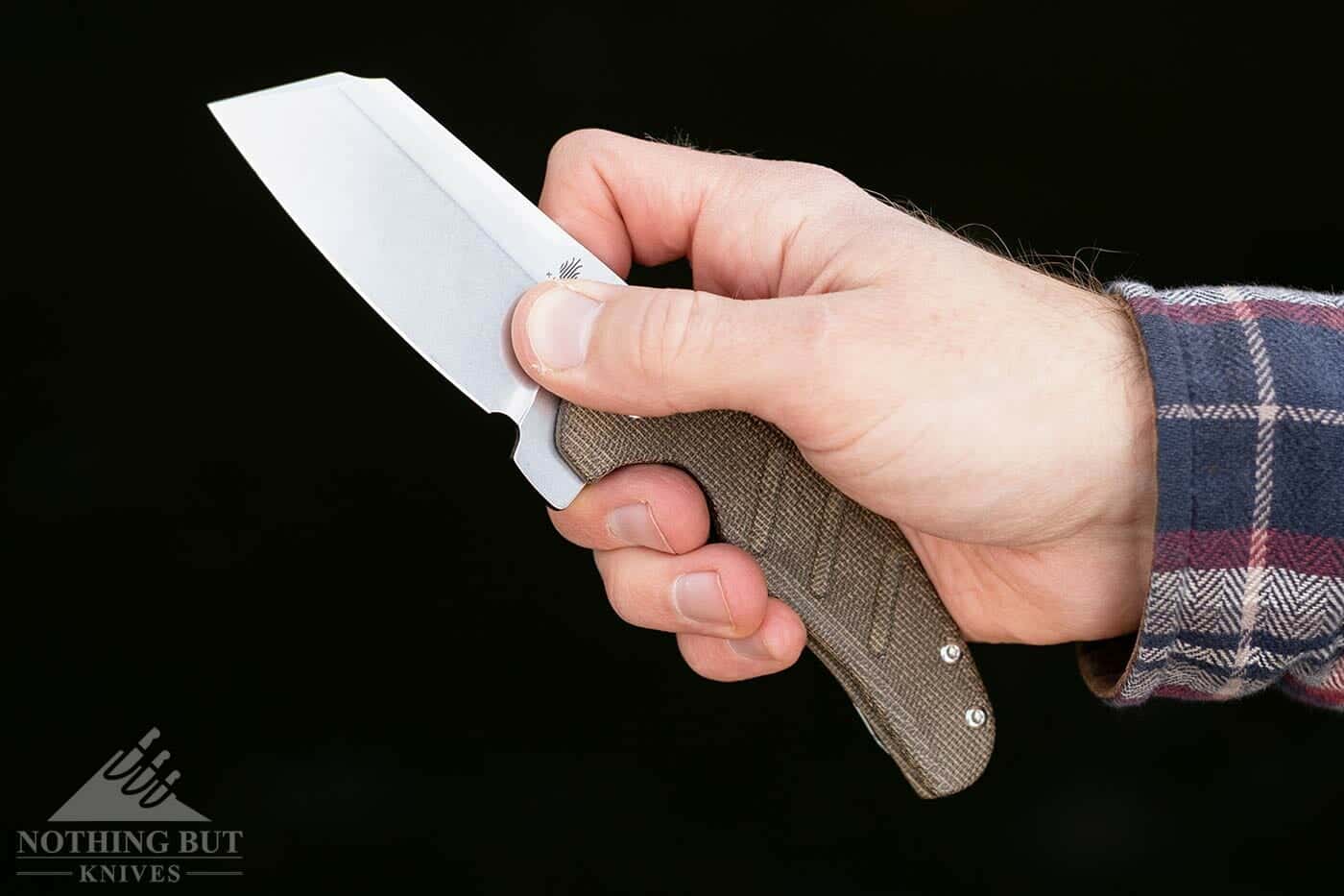 A man's hand holding the Kizer Sheepdog in a pinch grip. 