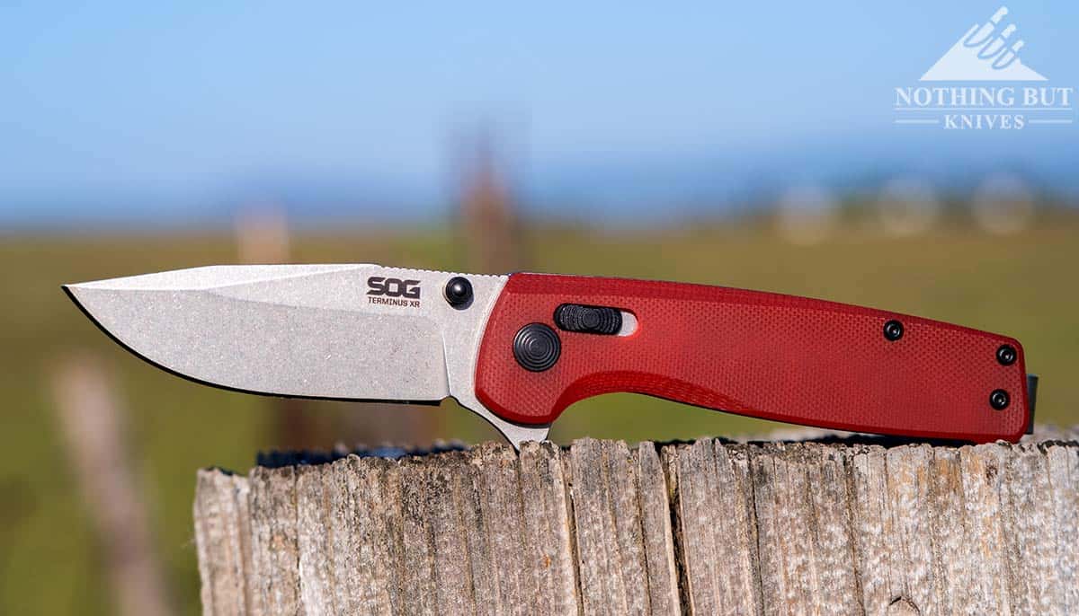 The Best D2 Steel Knives And What Makes Them Great - Image 21 The SOG Terminus XR With a D2 steel blade on a fence post outdoors.