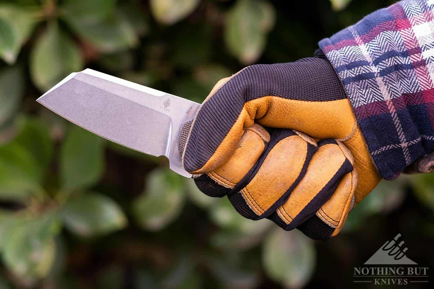 A man's gloved hand holding the Kizer Sheepdog outdoors. 