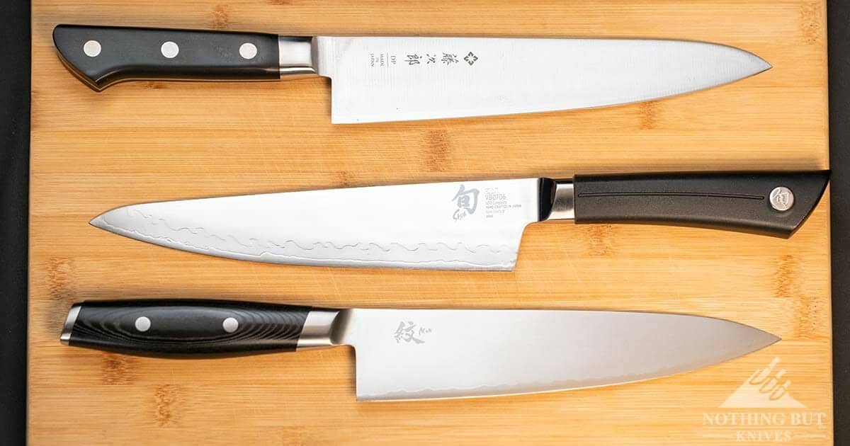 Yaxell Mon Gyuto 8 Inch Chef Knife Review - Image 8 The Tojiro DP, Shun Sora and Yaxel Mon chef knives togethor on a wooden cutting board.