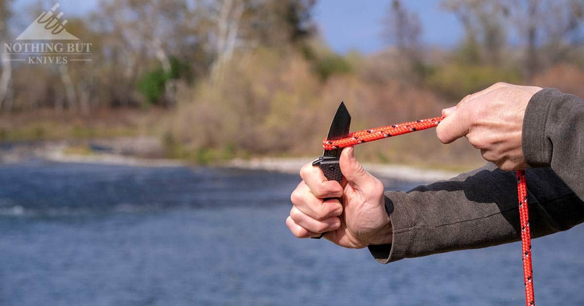 A pocket knife about to slice through a rope. 