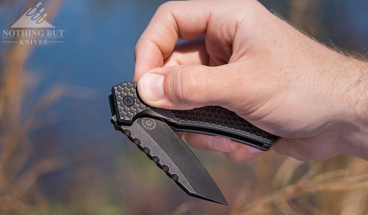 A man's hand flipping open the Off-Grid Black Mamba folding knife. 