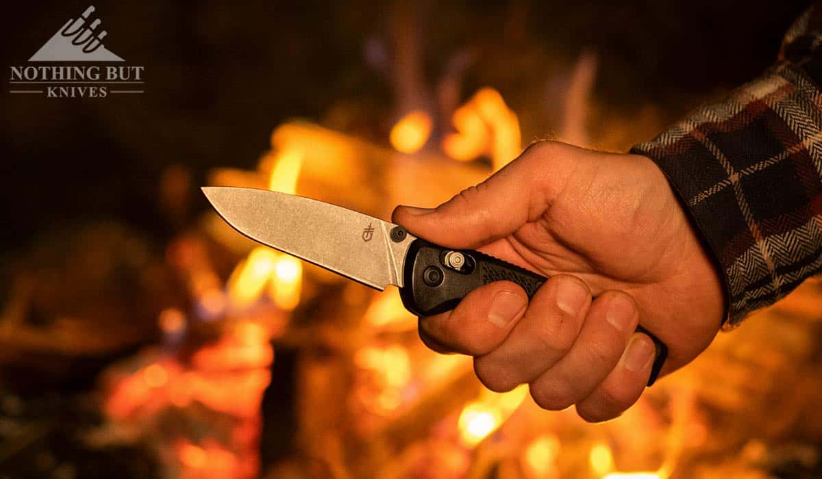The Gerber Sedulo in a man's hand with a campfire in the background.